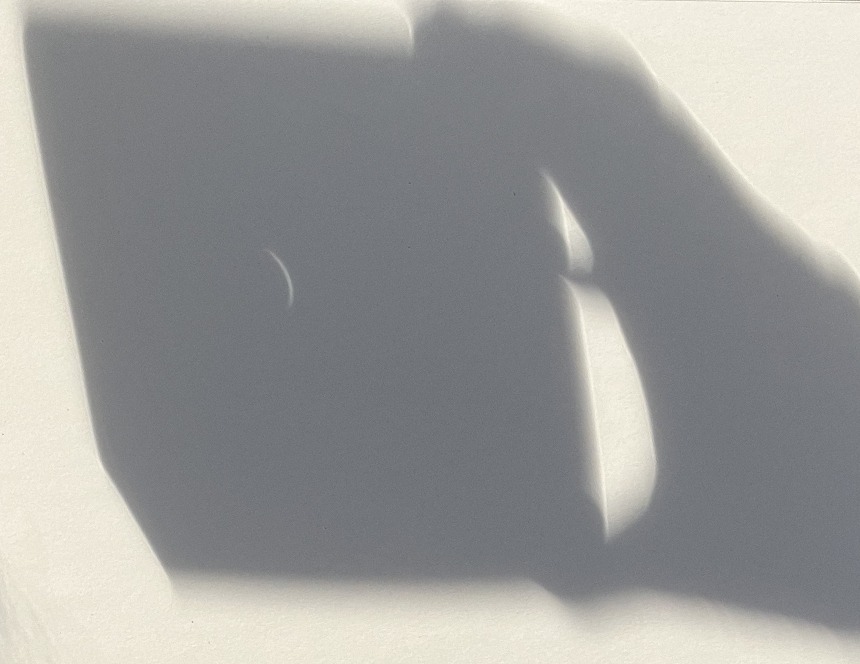 This photograph shows shadows: my hand holding the milk carton with the pierced foil.